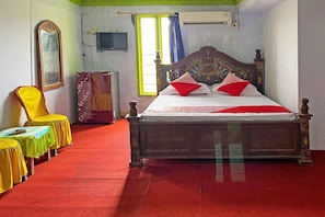 A room with a bed, a chair, a table, and a television. - 92326 Hotel Melati Bm Pangkep (Makassar)