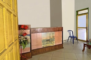 Ein Empfangsbereich mit einer Fliesenwand, einem blauen Kunststoffstuhl und einem Holztisch.