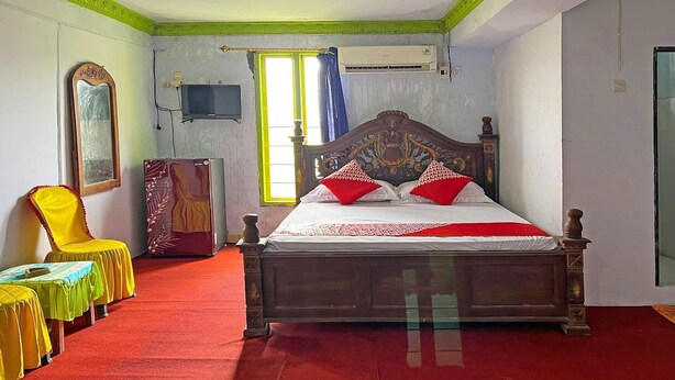 Um quarto com cama, uma cadeira, uma mesa e uma televisão.