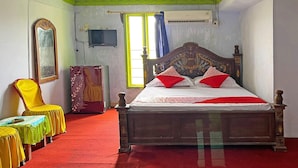 Um quarto com uma cama, uma cadeira, uma mesa e uma televisão.