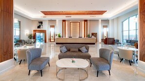 A modern lobby with a reception desk, seating area, and large windows. - Pickalbatros Vita Resort Portofino (Marsa Alam)