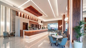 A modern hotel lobby with a reception desk, seating area, and large windows. - Pickalbatros Vita Resort Portofino (Marsa Alam)