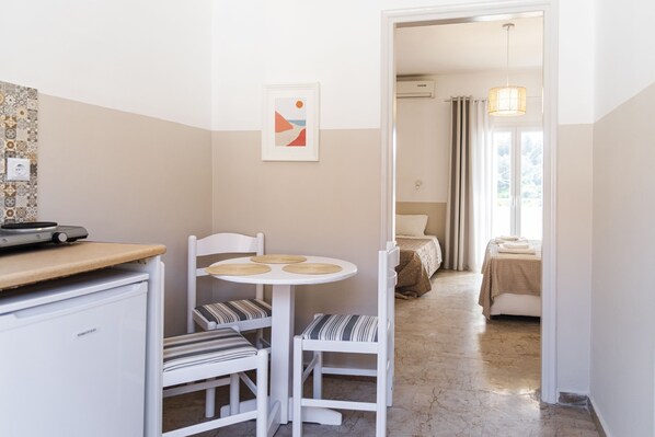 Ein kleines Zimmer mit Küchenzeile, einem Essbereich mit Tisch und Stühlen, einem Bett mit Fenster und einem Badezimmer mit Duschvorhang.