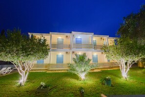 A two-story building with a balcony on the upper floor, a well-maintained lawn, and trees. - Eleonas Bohotel & Annex Apartments (Corfu)