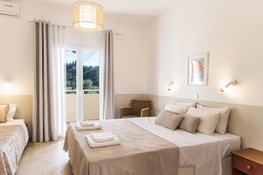 A hotel room with a bed, a chair, a desk, a window with curtains, and a wall-mounted picture. - Eleonas Bohotel & Annex Apartments (Corfu)