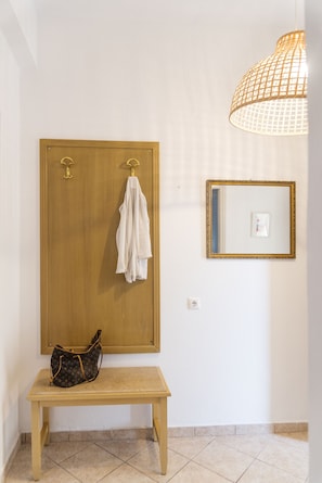 A bathroom with a wooden bench, a hanging towel, a Louis Vuitton bag, a mirror with a gold frame, and a hanging light fixture. - Eleonas Bohotel & Annex Apartments (Corfu)