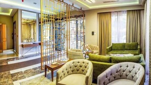 Een hotelkamer met zithoek, decoratieve roomdivider en uitzicht door een raam.