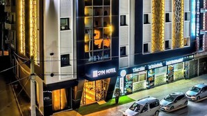 Een modern hotel met een opvallende ingang, meerdere verdiepingen en een zichtbaar restaurant gelijkvloers.