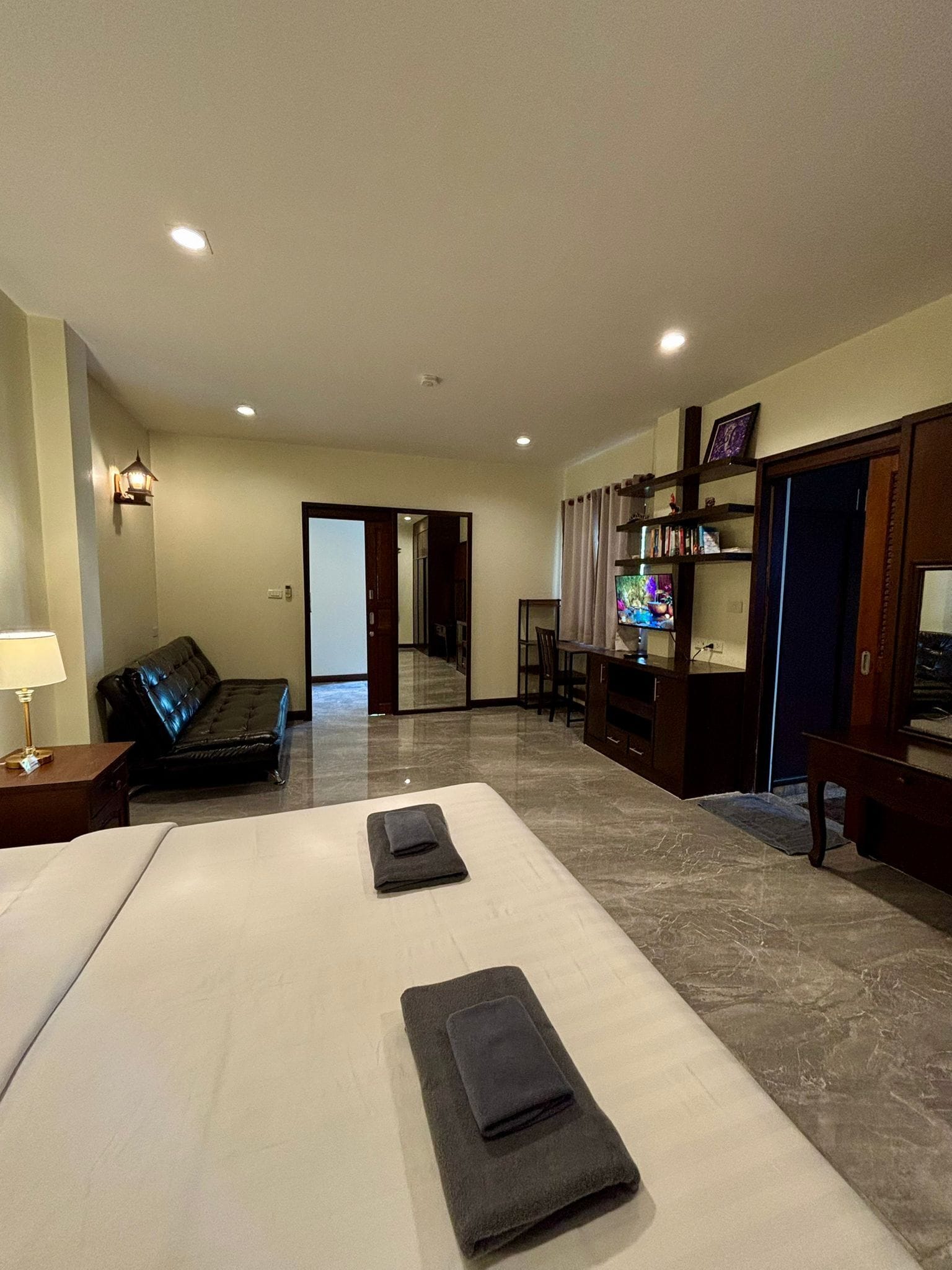 Una habitación de hotel con cama, sofá, televisor y escritorio.
