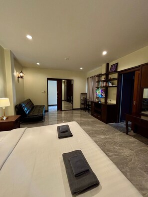 Una habitación de hotel con cama, sofá, televisor y escritorio.