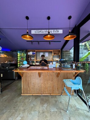 Un bar con mostrador de madera, luces colgantes y un letrero en un idioma extranjero.