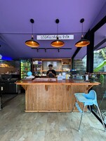 A bar with a wooden counter, hanging pendant lights, and a sign in a foreign language.