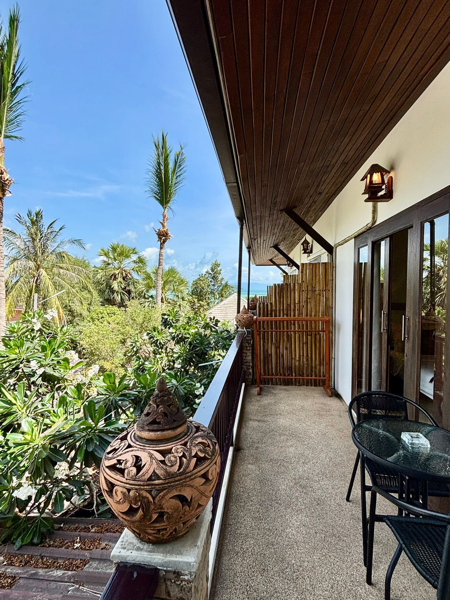Un espacio al aire libre techado con una mesa y sillas, una maceta decorativa y vista al mar.