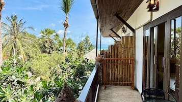 Un espacio al aire libre techado con una mesa y sillas, una maceta decorativa y vista al mar.