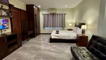 A hotel room with a bed, a TV, a sofa, and a wardrobe.