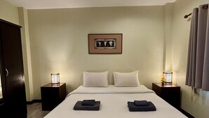 Ett hotellrum med en stor säng, två sängbord, en inramad tavla på väggen och en dörr till vänster.