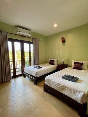 Habitación de hotel con dos camas, un balcón y un aire acondicionado.