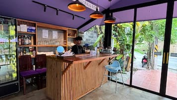 Zona de bar con mostrador de madera, estantes con botellas y un amplio ventanal con vistas a zonas verdes.