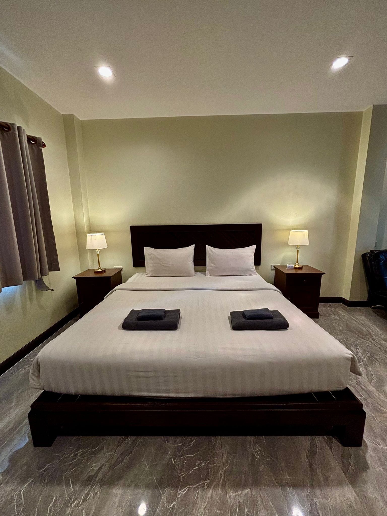 Quarto de hotel com uma cama grande, duas mesas de cabeceira e uma cabeceira.