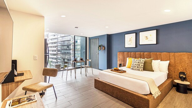 A modern hotel room with a large bed, a desk, and a balcony with a city view. - Casa Sócrates By Kukun (Mexico City)