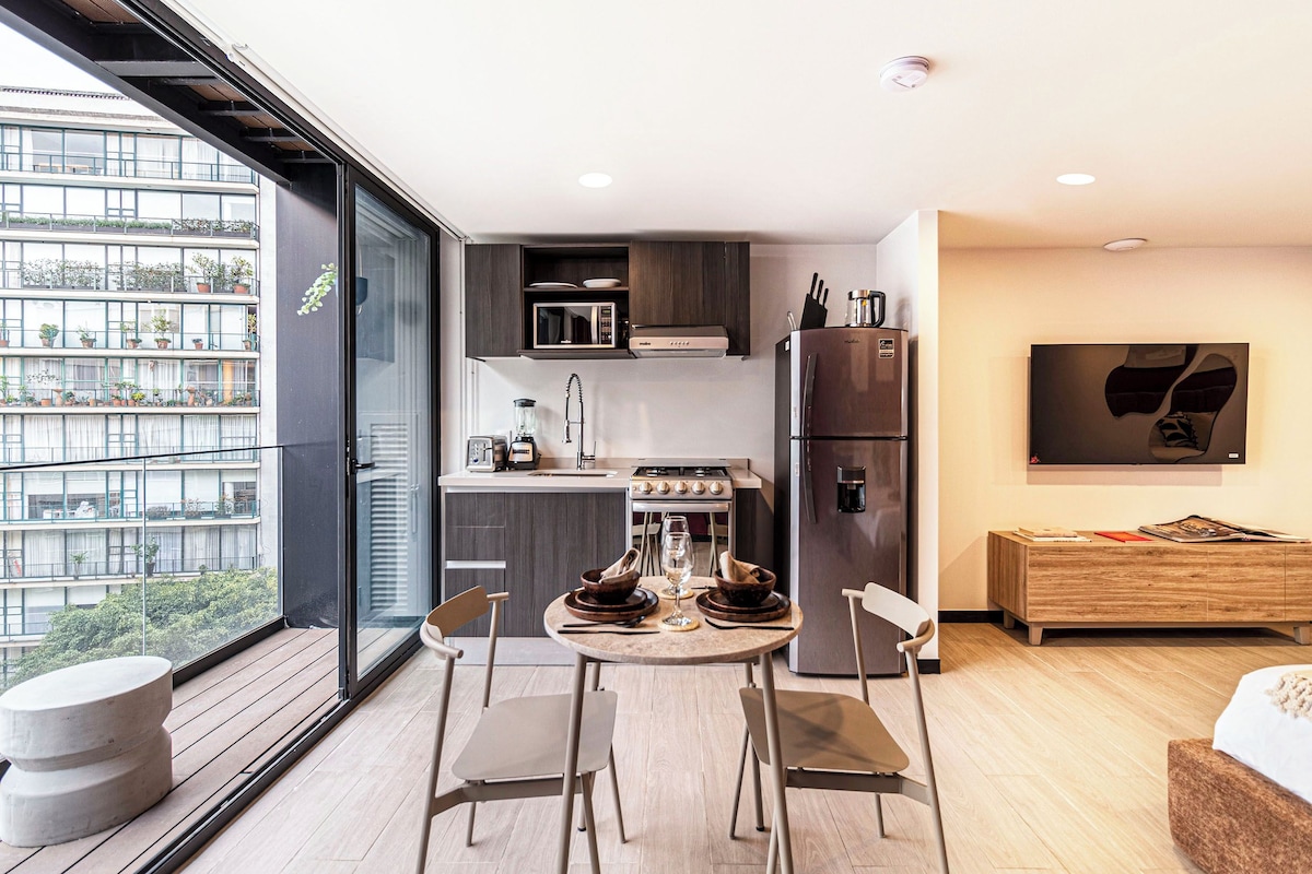A modern kitchen with a dining area, a built-in oven, and a refrigerator.