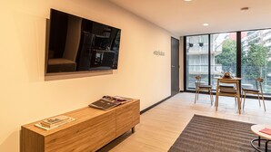 A modern living room with a flat-screen TV mounted on the wall, a wooden console table with magazines, and a dining area with a table and chairs. - Casa Sócrates By Kukun (Mexico City)