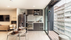 A modern kitchen with a built-in oven, microwave, and sink. There is a dining area with a table and chairs, and a balcony with a view of the city. - Casa Sócrates By Kukun (Mexico City)
