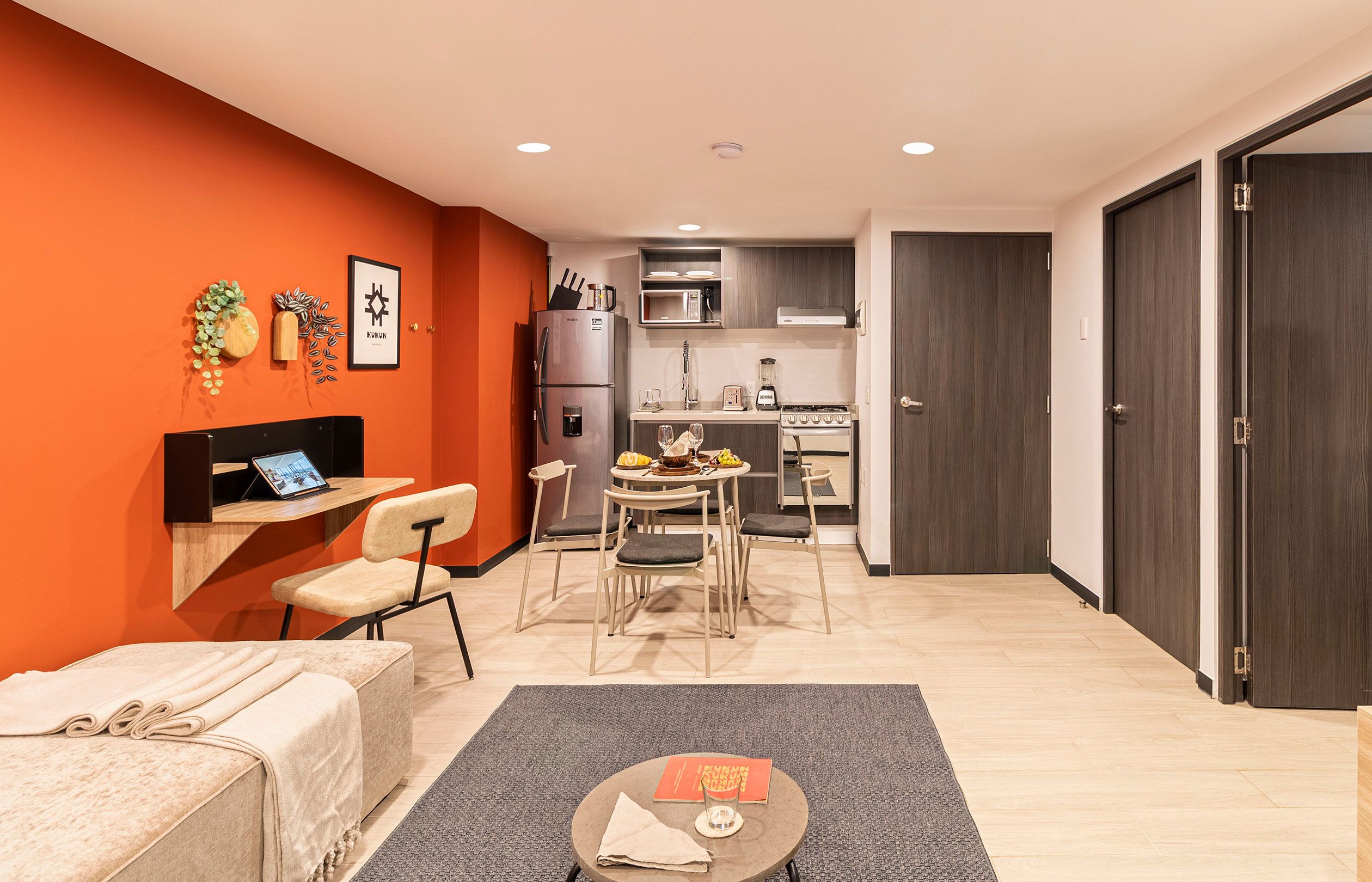 A compact living space with a kitchenette, a dining area, and a seating area with a sofa and chairs.