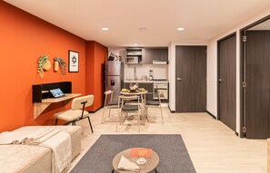 Un espacio habitable compacto con kitchenette, una zona de comedor y un área de descanso con sofá y sillones.