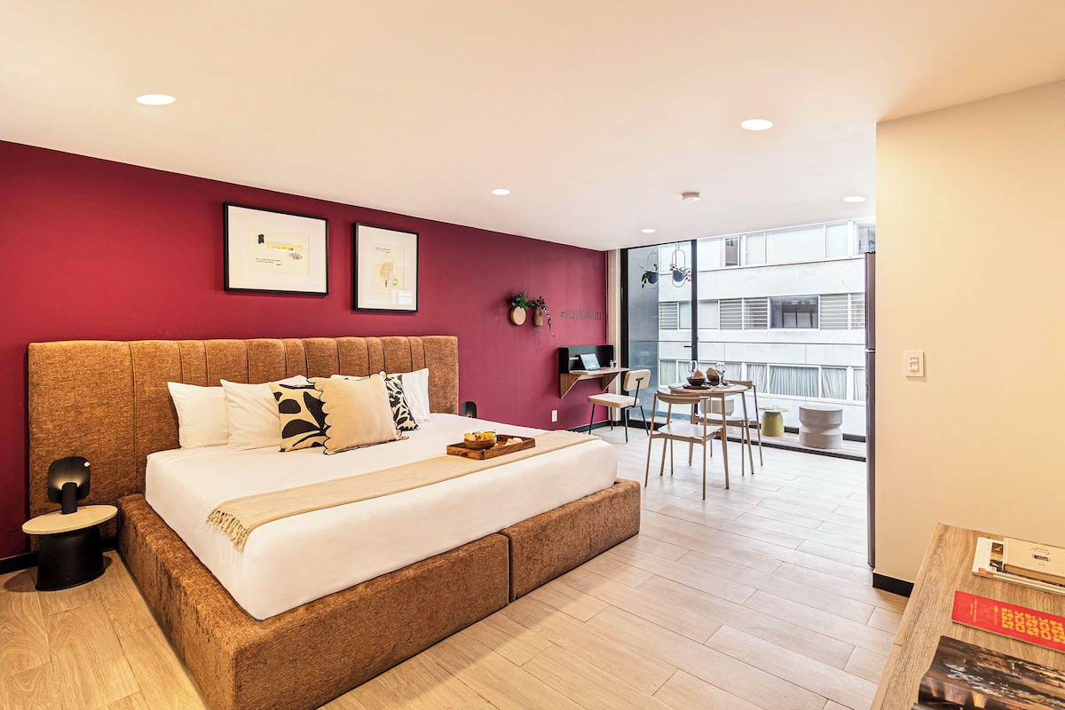 Habitación de hotel moderna con una cama grande, un escritorio y vistas a la ciudad.