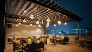 An outdoor seating area with wicker furniture and pendant lighting.
