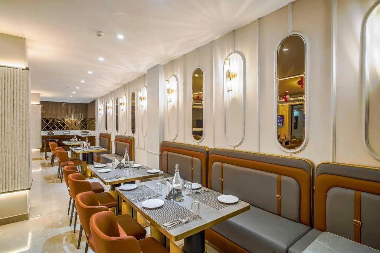 A dining area with long tables, cushioned booths, and wall-mounted light fixtures.