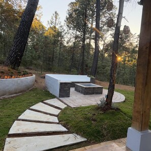 A stone pathway leading to a modern outdoor seating area surrounded by trees. - Cima Boreal Chalet (Tapalpa)