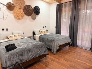 A room with two beds, a wooden floor, and decorative wall art. - Cima Boreal Chalet (Tapalpa)