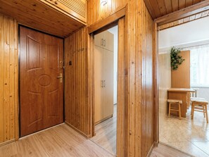 A wooden interior with a door, a cabinet, and a small table with chairs. - Pod Lipami Cozy Apartment (Poznań)