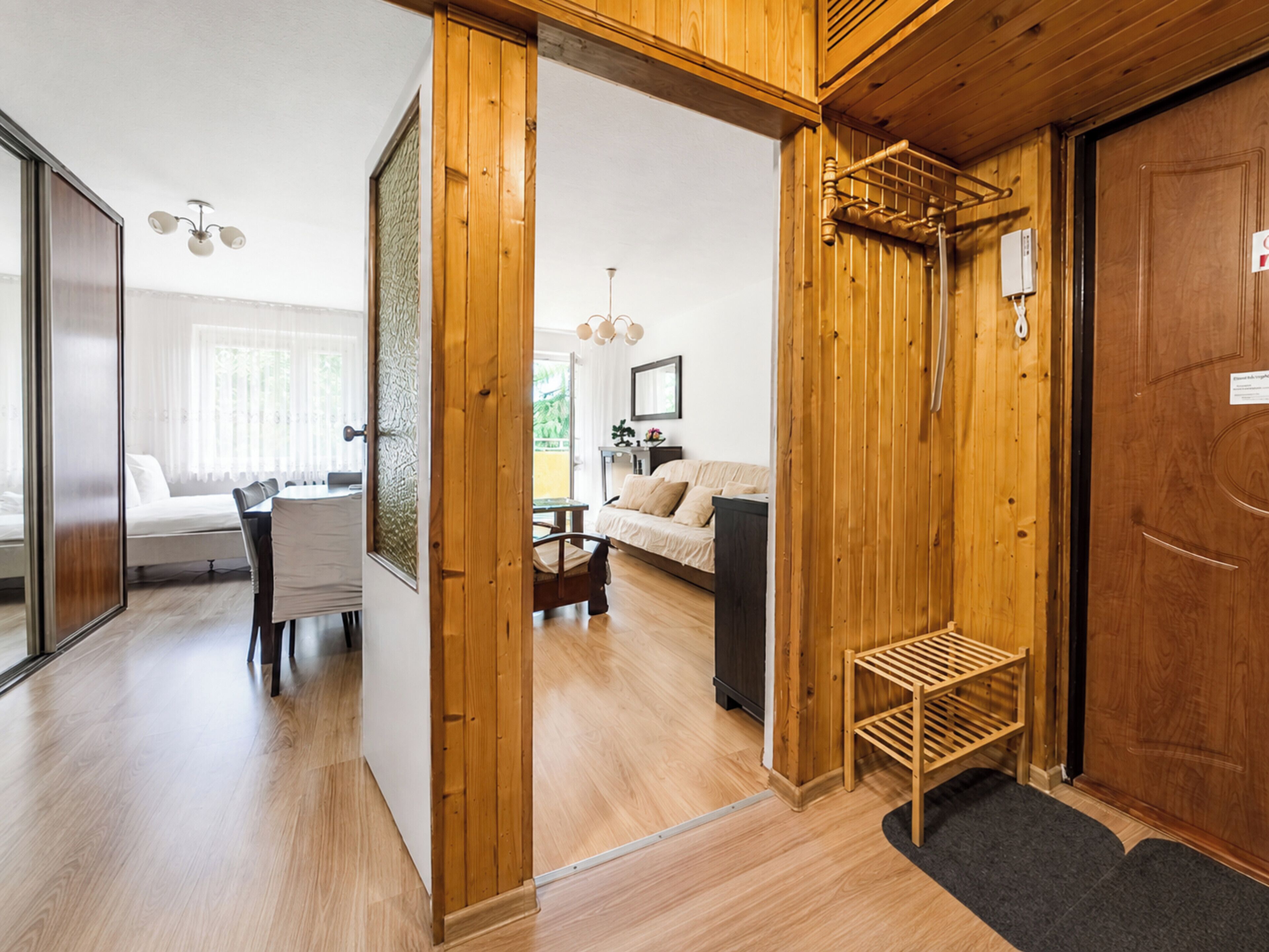 Un intérieur en bois comprenant un coin repas, un canapé et une porte avec une pancarte.