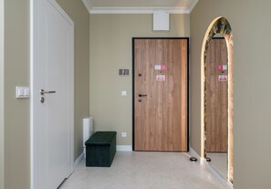 A hallway with a wooden door, a bench, and a mirror on the wall. - Chmielna Signature Apartment (Warszawa)