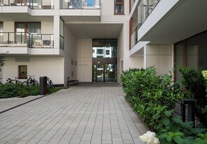A modern building entrance with a covered walkway, potted plants, and bicycles parked outside. - Chmielna Signature Apartment (Warszawa)