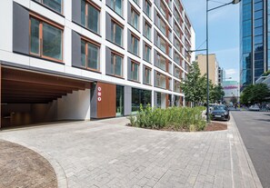 A modern building with a covered entrance, a clear pedestrian pathway, and a small garden area. - Chmielna Signature Apartment (Warszawa)