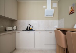 A modern kitchen with white cabinetry, a built-in oven, and a coffee maker. - Chmielna Signature Apartment (Warszawa)