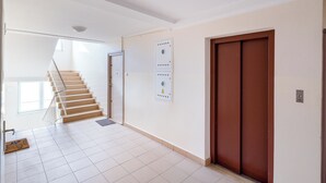 A hallway with a staircase leading to an upper floor, a door with a safety interlock, and a wall-mounted interlock panel. - Solec Powiśle Standard Apartment (Warszawa)