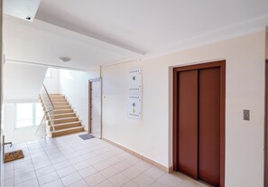 Ein Korridor mit einer Treppe, die zu einer oberen Etage führt, einer Tür mit Sicherheitsverriegelung und einer wandmontierten Verriegelungstafel.