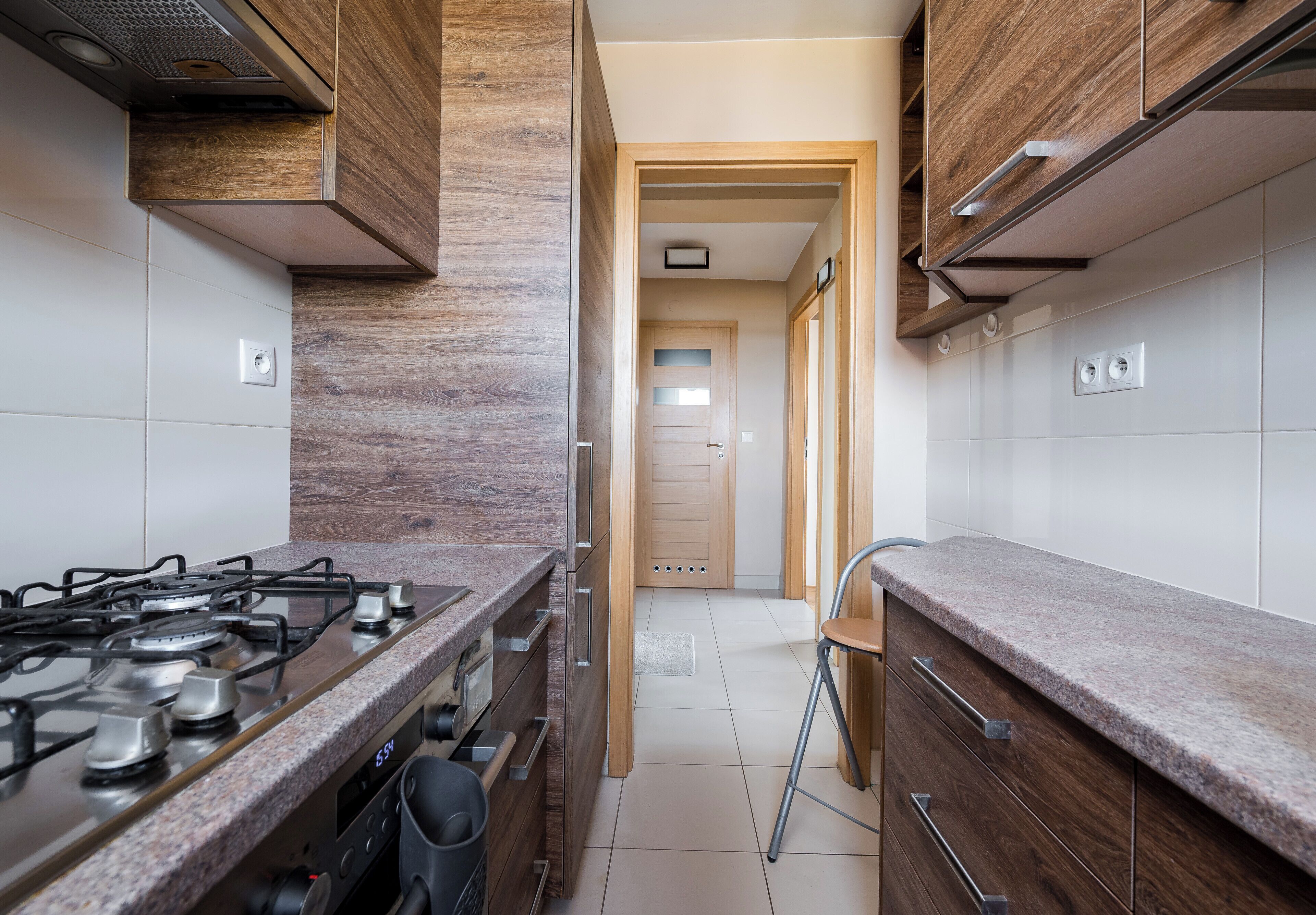 Une cuisine équipée d’une cuisinière à gaz, de meubles de rangement en bois et d’un dosseret carrelé.