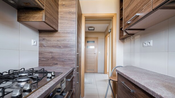 A kitchen with a gas stove, wooden cabinets, and a tiled backsplash. - Solec Powiśle Standard Apartment (Warszawa)