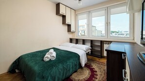 A hotel room with a bed, a desk, a window with a view, and a radiator. - Solec Powiśle Standard Apartment (Warszawa)