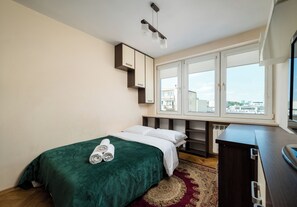 Ein Hotelzimmer mit Bett, Schreibtisch, Fenster mit Blick und Heizkörper.