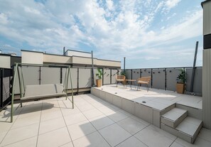 Terraço no telhado com balanço, área de estar ao ar livre e plantas em vasos.
