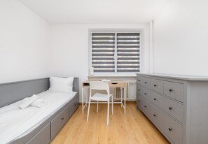 Ein kleines Schlafzimmer mit einem Einzelbett, einem Schreibtisch und einem Stuhl.