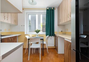 Eine kleine Küche mit Esstisch, Stühlen und einem Fenster mit Vorhängen.