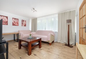 Ein Wohnzimmer mit Holzboden, zwei Sofas, einem Couchtisch, einem Fernseher und einer Stehlampe.